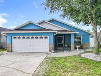 Charming blue single-story home with a well-manicured lawn and a white two-car garage at 1515 Oak Hill Trl, Kissimmee, FL 34747