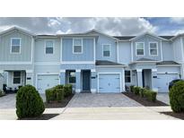 Charming light blue two-story townhome featuring a one-car garage and manicured landscaping at 4634 Tribute Trl, Kissimmee, FL 34746