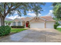 Charming single-story home featuring a well-manicured lawn, arched windows, and a three-car garage at 651 Regina Cir, Oakland, FL 34787