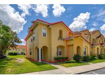 Inviting two-story townhome featuring a terracotta roof and lush landscaping at 7638 Long Island Dr, Kissimmee, FL 34747