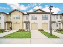 New townhomes featuring attached garages, well-manicured lawns and sidewalks on a beautiful, sunny day at 816 Longboat Dr, Davenport, FL 33896