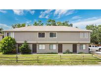 Two-story condo with neutral colors and a split rail fence around a lawn at 12155 Pepperdine Pl, Orlando, FL 32826