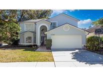 Charming two-story home with attached two-car garage, manicured lawn and mature trees at 13129 Cog Hill Way, Orlando, FL 32828