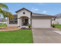 Charming one-story home featuring a two-car garage, lush landscaping, and inviting front entrance with covered porch at 1864 Castleton Dr, St Cloud, FL 34771