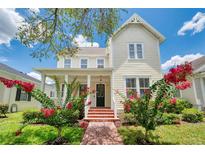 Charming two-story home with a brick walkway and beautiful red flowers, creating a welcoming entrance at 205 N Village St, Celebration, FL 34747