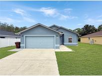 Charming single-story home features a well-manicured lawn, a two-car garage, and a classic facade at 2444 Oak Mill Dr, Kissimmee, FL 34744