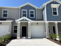 Modern two-story townhome featuring an attached garage, blue accents, and well-maintained landscaping at 2626 Skyline Loop, Kissimmee, FL 34758