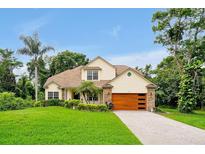 Inviting two-story home with a well-manicured lawn, a contemporary wood-tone garage door, and lush landscaping at 3109 Harvest Ln, Kissimmee, FL 34744