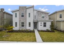 Modern two-story home featuring a textured stone facade and well-maintained front lawn at 4547 Narrative Ln, Kissimmee, FL 34746