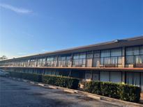 Low angle shot of a multi-unit exterior with a long row of rooms, black railing, and partial parking lot at 7900 S Orange Blossom Trl # 2136, Orlando, FL 32809
