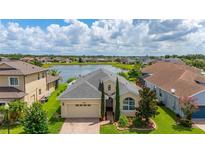 Inviting home features lush landscaping, a brick driveway and attached two car garage with a picturesque lake view at 2823 Sail Breeze Way, Kissimmee, FL 34744