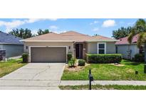 Charming single Gathering home featuring a two-car garage and well manicured lawn with shrubbery at 2829 Shelburne Way, St Cloud, FL 34772