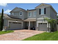 Charming two-story home featuring a brick driveway, two-car garage, and solar panels at 3252 Jackson Bluff Way, Clermont, FL 34711