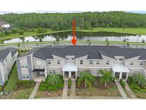 An aerial view of a modern townhome with gray facade, dark roof, and manicured landscaping near a serene pond at 4403 Scene Ln, Kissimmee, FL 34746
