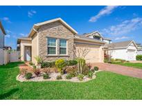 Charming single-Gathering home featuring a stone facade and meticulously landscaped front yard with vibrant greenery at 1456 Sourwood Dr, Ocoee, FL 34761
