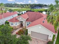 Beautiful home featuring a red roof, complemented by lush landscaping and a serene water view at 324 Sorrento Rd, Poinciana, FL 34759
