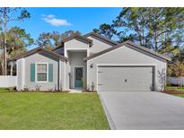 Charming home featuring a two-car garage, fresh lawn, neutral paint, and teal door at 4711 Sw 136Th Pl, Ocala, FL 34473