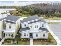 Modern two-story home featuring stone accents, well-kept landscaping, and a view of the nearby lake at 2901 Protagonist St, Kissimmee, FL 34746