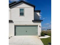 Two-story home with a sage green garage door and a clean white concrete driveway at 902 Poppy Ln, Dundee, FL 33838