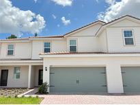Charming two-story home featuring a gray two-car garage, a red tile roof and a brick driveway at 567 Bay Leaf Dr, Poinciana, FL 34759