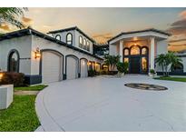 Elegant estate features a circular driveway, manicured landscaping, and an attached three-car garage at 9202 Bay Point Dr, Orlando, FL 32819