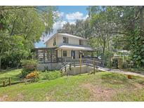Charming two-story home featuring a large porch and lush, mature landscaping around the property at 3603 Cr 626N, Bushnell, FL 33513