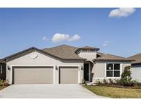 Charming single-story home featuring a three-car garage, manicured lawn, and inviting entryway at 4457 Sw 84Th Street Rd, Ocala, FL 34476