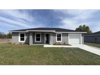 Charming gray home with a well-manicured lawn and a freshly sealed driveway at 13371 Sw 112Th Pl, Dunnellon, FL 34432