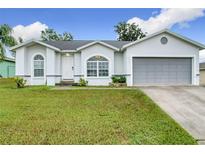 Charming single-story home with a well-manicured lawn, grey door, and a two-car garage at 7713 Manor Dr, Lakeland, FL 33810
