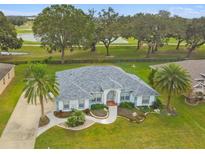 Stunning single-story home featuring a well-manicured lawn, palm trees, and golf course views at 5407 County Road 125, Wildwood, FL 34785