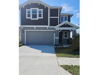 Charming two-story home with gray siding, a two-car garage, and a well-manicured lawn under a bright blue sky at 6652 Great Bear Dr, Lakeland, FL 33805