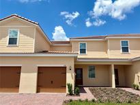 Charming tan two-story townhome with red tile roof and two-car garage at 576 Bay Leaf Dr, Poinciana, FL 34759