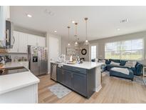 Open-concept kitchen features a center island with pendant lighting and stainless steel appliances at 1624 Pelican Dr, Davenport, FL 33896