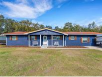 Charming blue single-story home with a red roof, covered porch, and well-maintained front yard at 901 Swann Dr, Lakeland, FL 33809