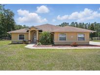 Charming single-story home with a well-manicured lawn and beautiful landscaping at 4995 County Road 121D, Wildwood, FL 34785