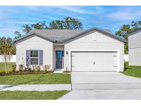 Charming single-story home featuring a two-car garage, well-manicured lawn, and stylish blue accents at 13454 Leaping Water Way, Astatula, FL 34705