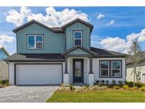 Charming two-story home featuring a blue exterior, well-manicured lawn, and an attached two-car garage at 6074 Sacred Oak Ave, Mount Dora, FL 32757