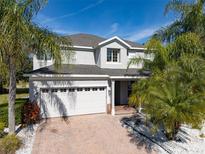 Two-story house with white garage door, landscaping, and palm trees at 13438 Davenham Pt, Orlando, FL 32832