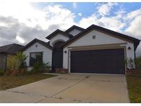 Charming single-story home with a well-maintained lawn and a two-car garage at 1051 Woodlark Dr, Haines City, FL 33844
