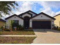 Charming single-story home with a two-car garage, manicured landscaping, and neutral color palette at 1051 Woodlark Dr, Haines City, FL 33844