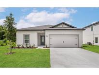 Charming single-Gathering home featuring a two-car garage, lush lawn, and freshly landscaped garden beds at 13469 Leaping Water Way, Astatula, FL 34705