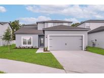Charming two-story home with gray exterior paint, well-manicured lawn, and two car garage at 13462 Leaping Water Way, Astatula, FL 34705