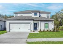 Charming two-story home with a two-car garage, well-manicured lawn, and a blue front door at 13466 Leaping Water Way, Astatula, FL 34705