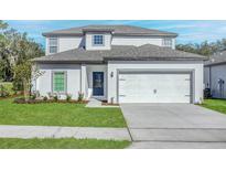 Charming two-story home featuring a blue door, white garage door, and well-manicured lawn at 13477 Leaping Water Way, Astatula, FL 34705