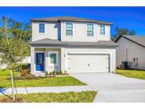 Charming two-story home featuring a two car garage, blue front door, and well maintained lawn at 13485 Leaping Water Way, Astatula, FL 34705