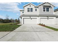 New two-story townhome with a two-car garage, modern facade, and a well-manicured front lawn at 520 Astera Winds Ln, Lake Mary, FL 32746