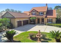 Two-story house with three car garage, fountain, and terracotta tile roof at 2024 Capri Ln, Mount Dora, FL 32757