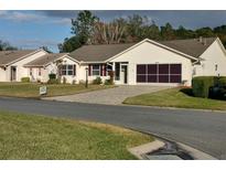 One-story home with paved driveway, landscaped yard, and screened enclosure at 26608 Racquet Cir, Leesburg, FL 34748