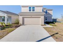 Two-story house with beige siding, attached garage, and landscaping at 4454 Petunia St, Lake Hamilton, FL 33851