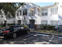 Two-story condo building with gray and white paint, balcony, and a black car parked in front at 4340 S Kirkman Rd # 905, Orlando, FL 32811